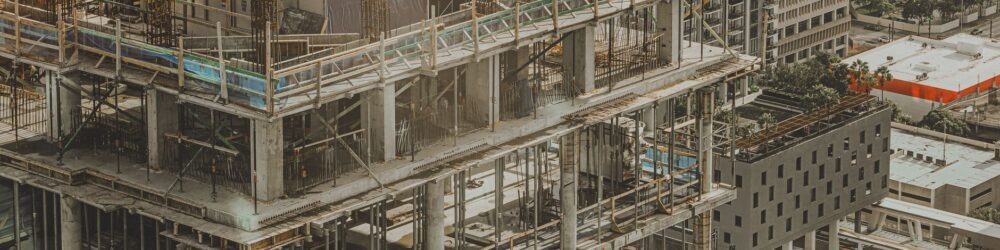 High-rise concrete frame under construction with formwork and scaffolding on the upper floors